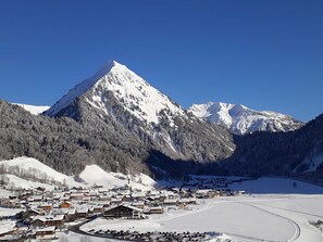 A mountain town with snow-covered buildings and a ski slope. - Triple Room (Type A) - Greber Christine - Frühstückspension Fernblick (Schoppernau)