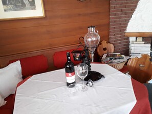 A table with a bottle of wine, a wine glass, and a candle holder. - Triple Room (Type A) - Greber Christine - Frühstückspension Fernblick (Schoppernau)