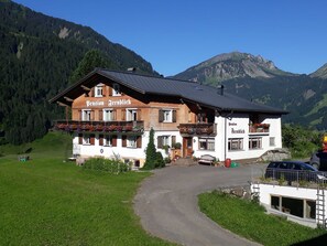 A two-story building with a sign reading 'Pension Fernblick' and a mountain backdrop.