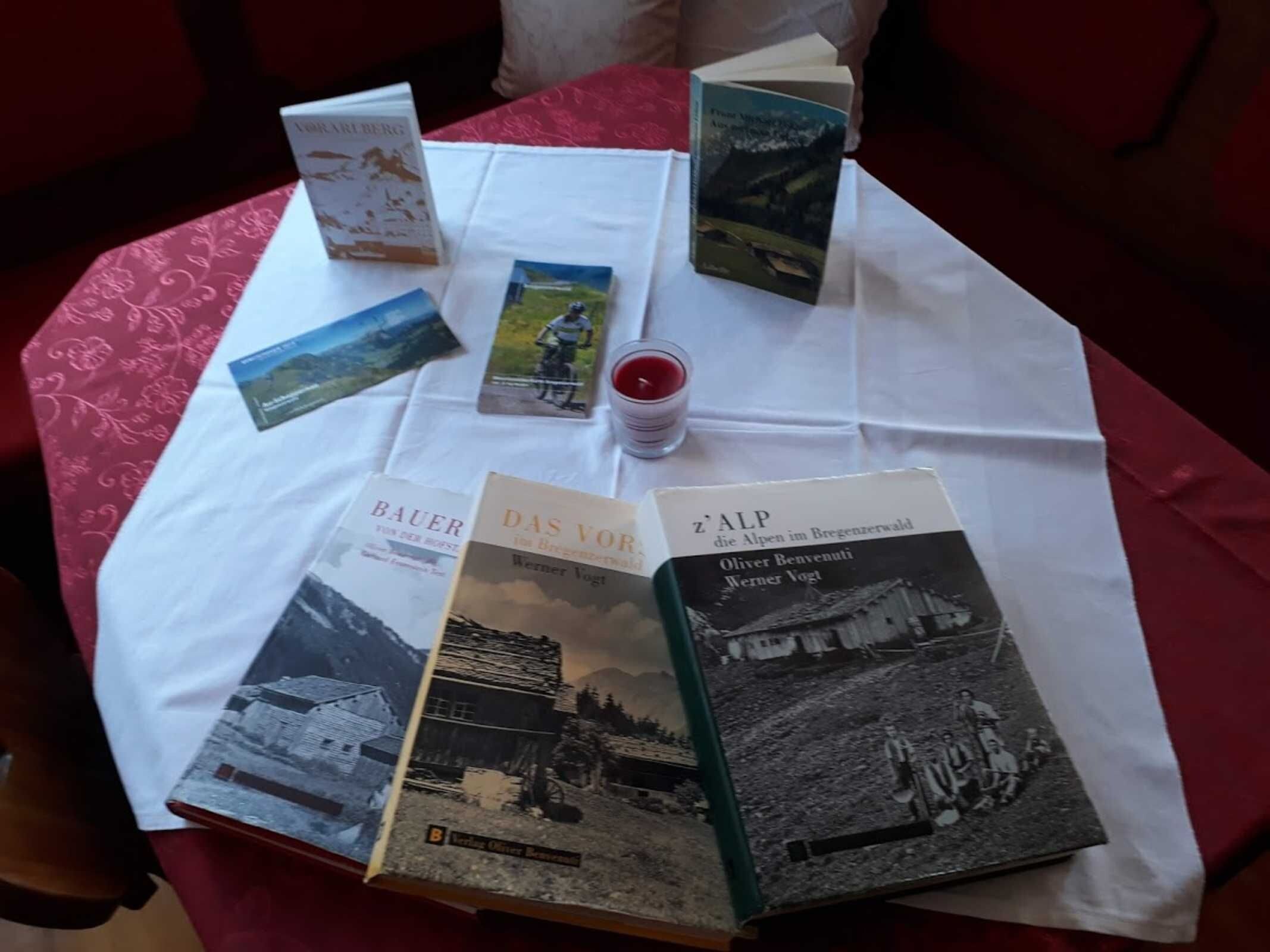 Une table sur laquelle se trouvent plusieurs livres et un verre contenant un liquide rouge.