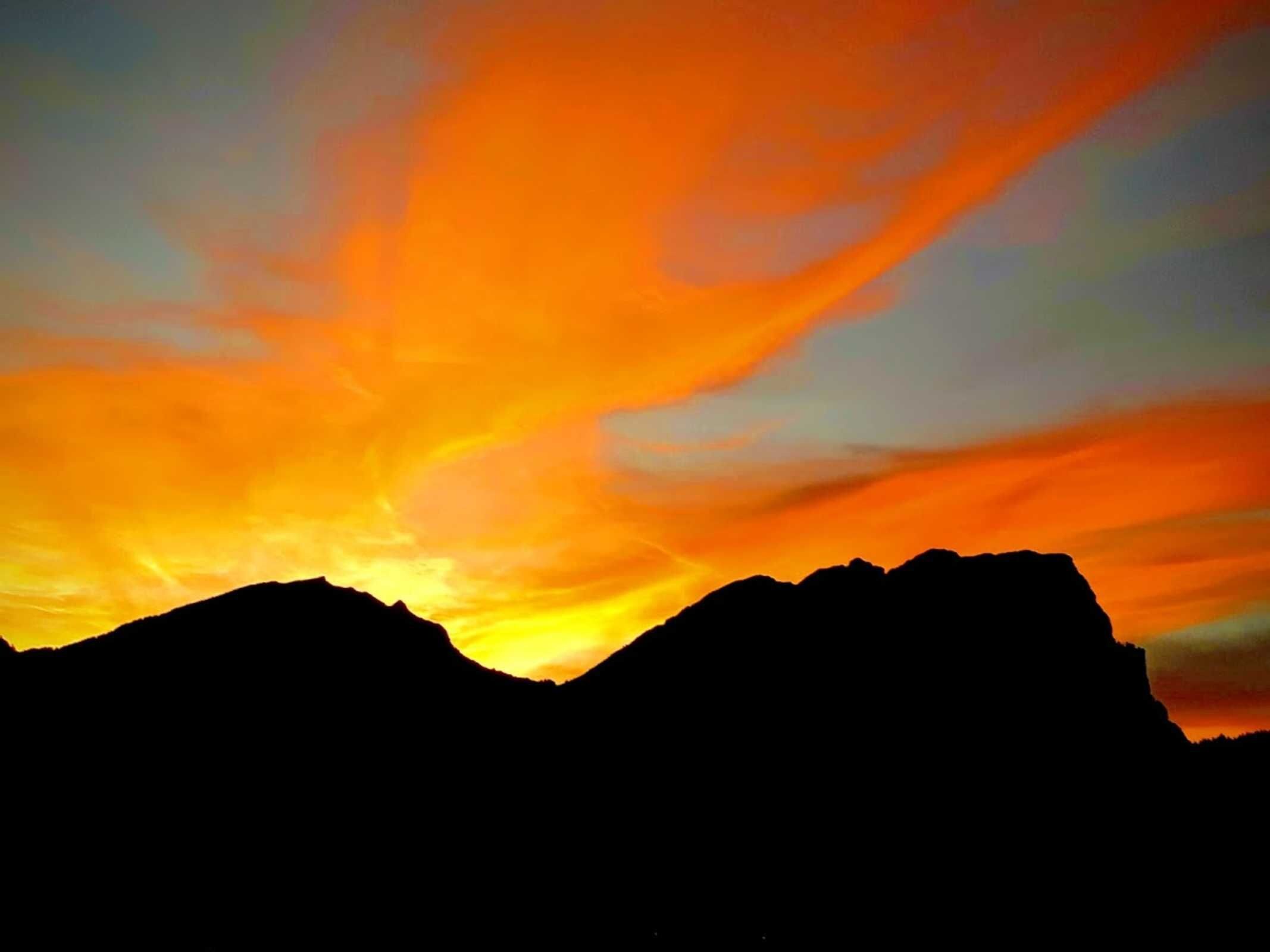 A mountain silhouette against a sunset sky.