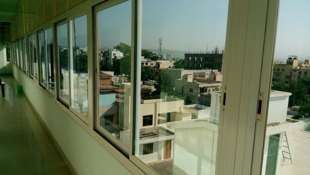 A corridor with large windows offering views of a residential area with multiple buildings and a clear sky.