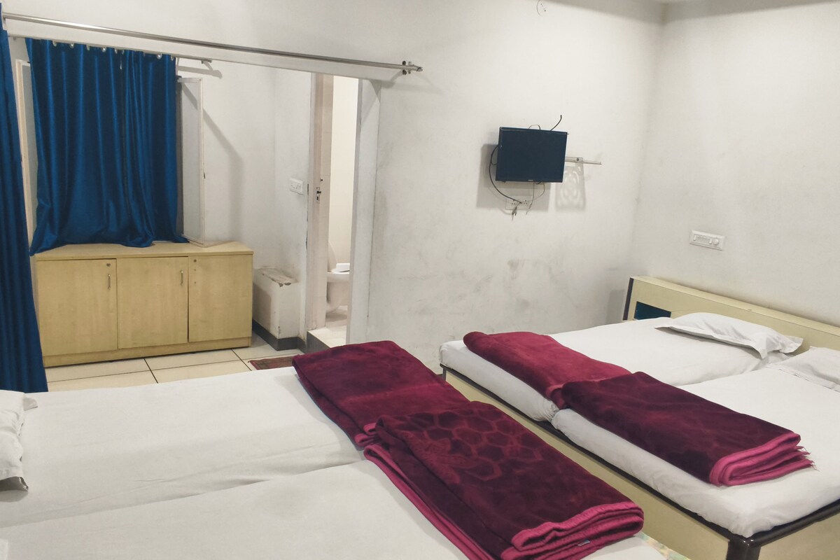 A room with two beds, a wooden cabinet, a television, and a curtain.