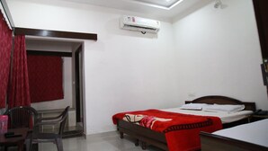 A small, well-lit room with a single bed, a desk, and a chair.