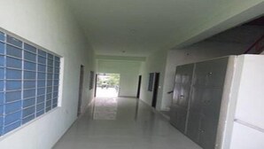 A long, narrow hallway with a tiled floor and a window with blue-tinted glass on the left.