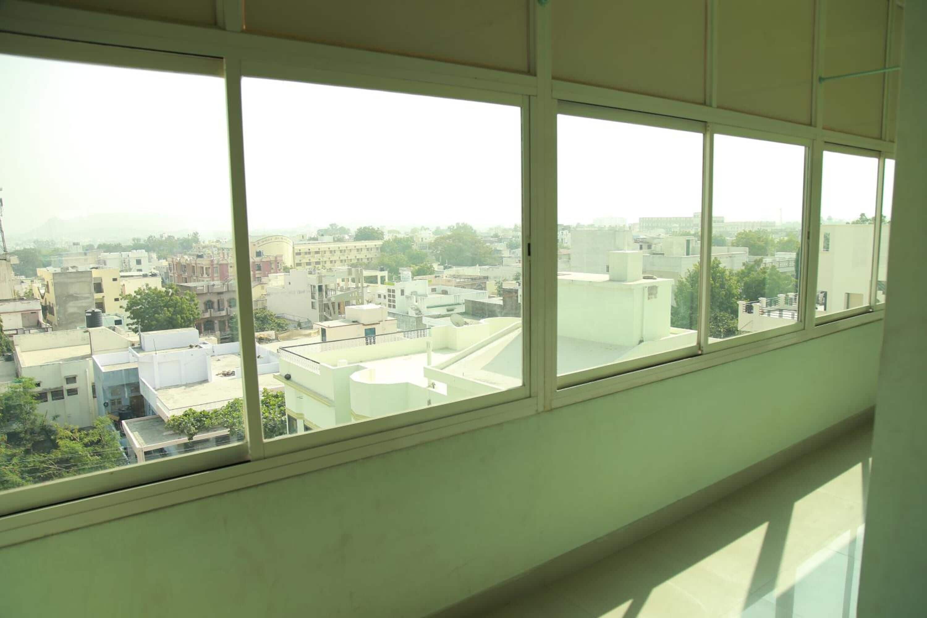 A room with large windows offering a view of a cityscape with various buildings and rooftops.