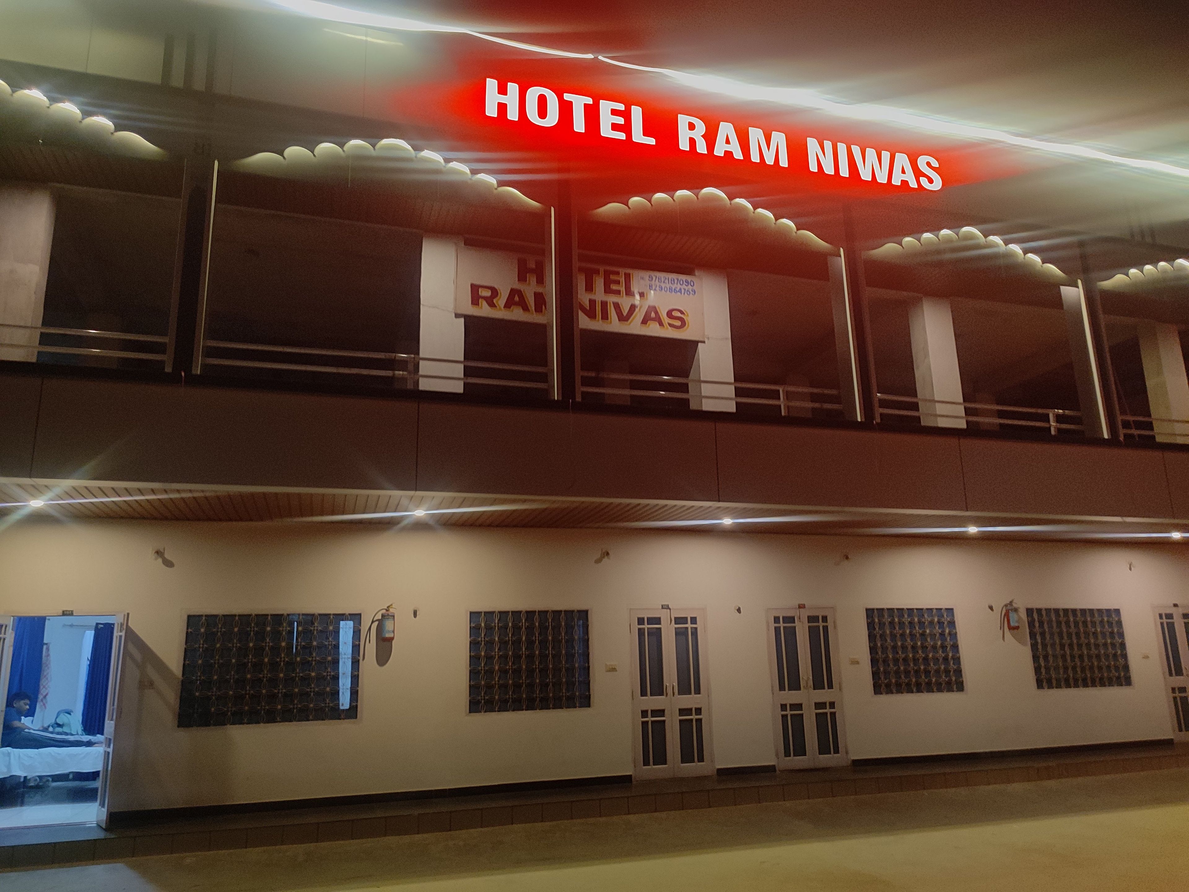 A hotel with a prominent sign reading 'HOTEL RAM NIWAS' and multiple windows with barred designs.