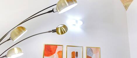 A ceiling with three pendant lights and three framed abstract paintings.