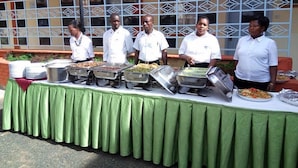 A buffet setup with multiple food stations and staff members. - Racecourse Inn Hotel (Eldoret)