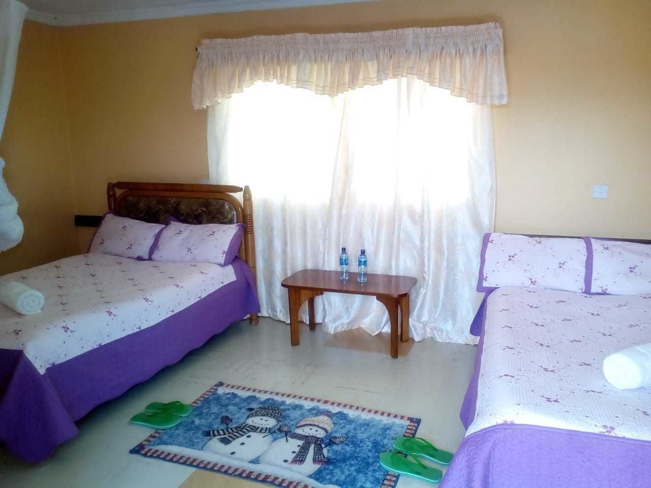 Een hotelkamer met twee bedden, een kleine tafel en een raam met gordijnen.