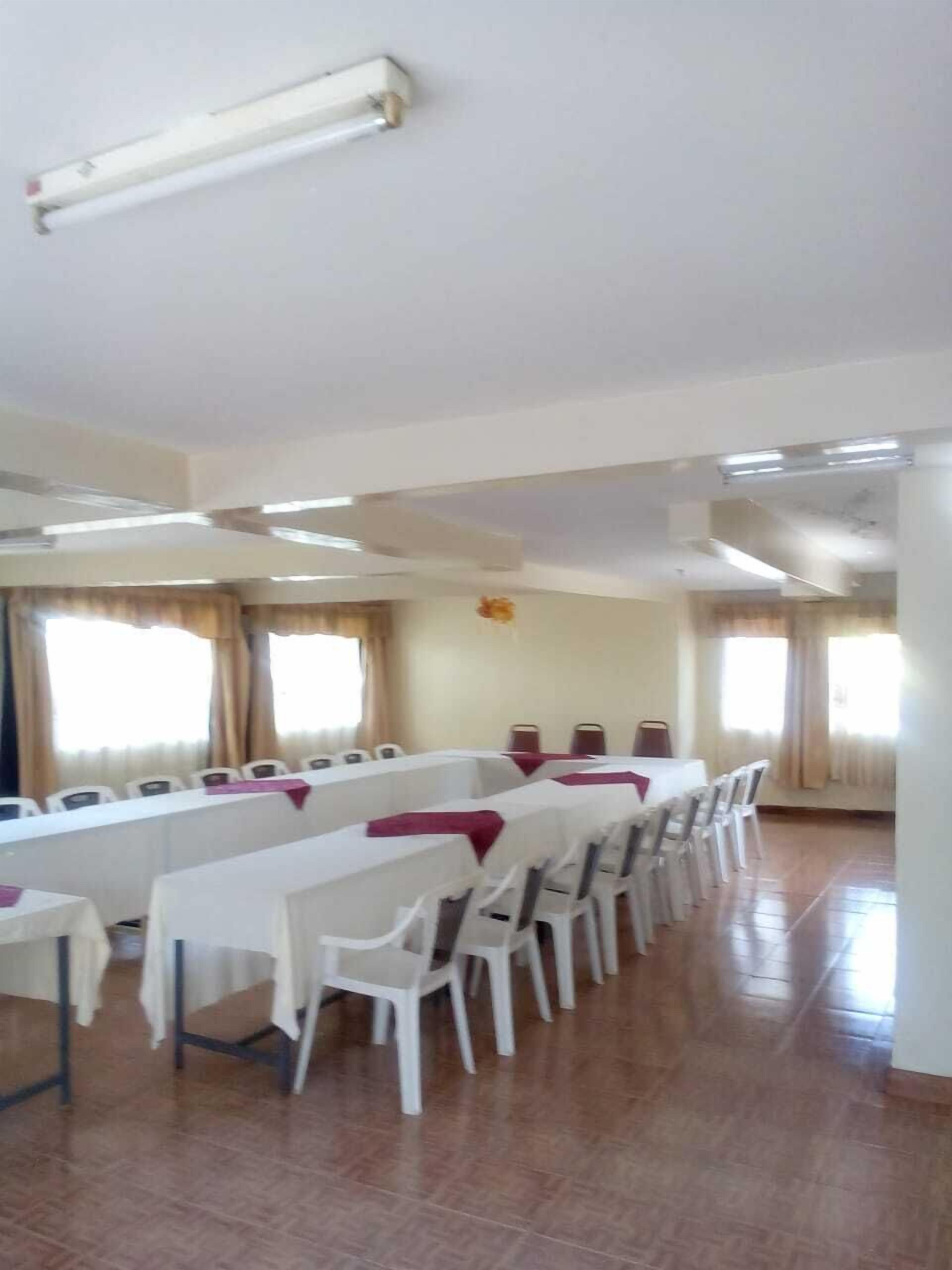 A conference room with a long table, white chairs, and a ceiling light fixture.