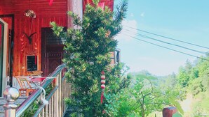 A wooden building with a red exterior, a balcony with potted plants, and a red lantern. - one step to heaven inn (Zhangjiajie)