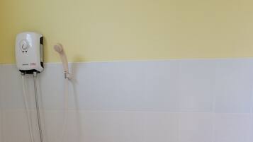 A bathroom with a toilet, a shower unit, and a white tiled wall.