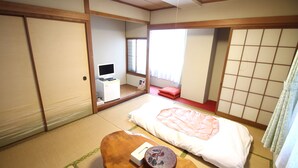 A traditional Japanese-style room with tatami flooring, a futon bed, a small wooden table, and sliding doors. - Royal Inn Shinyamaguchi (Yamaguchi)