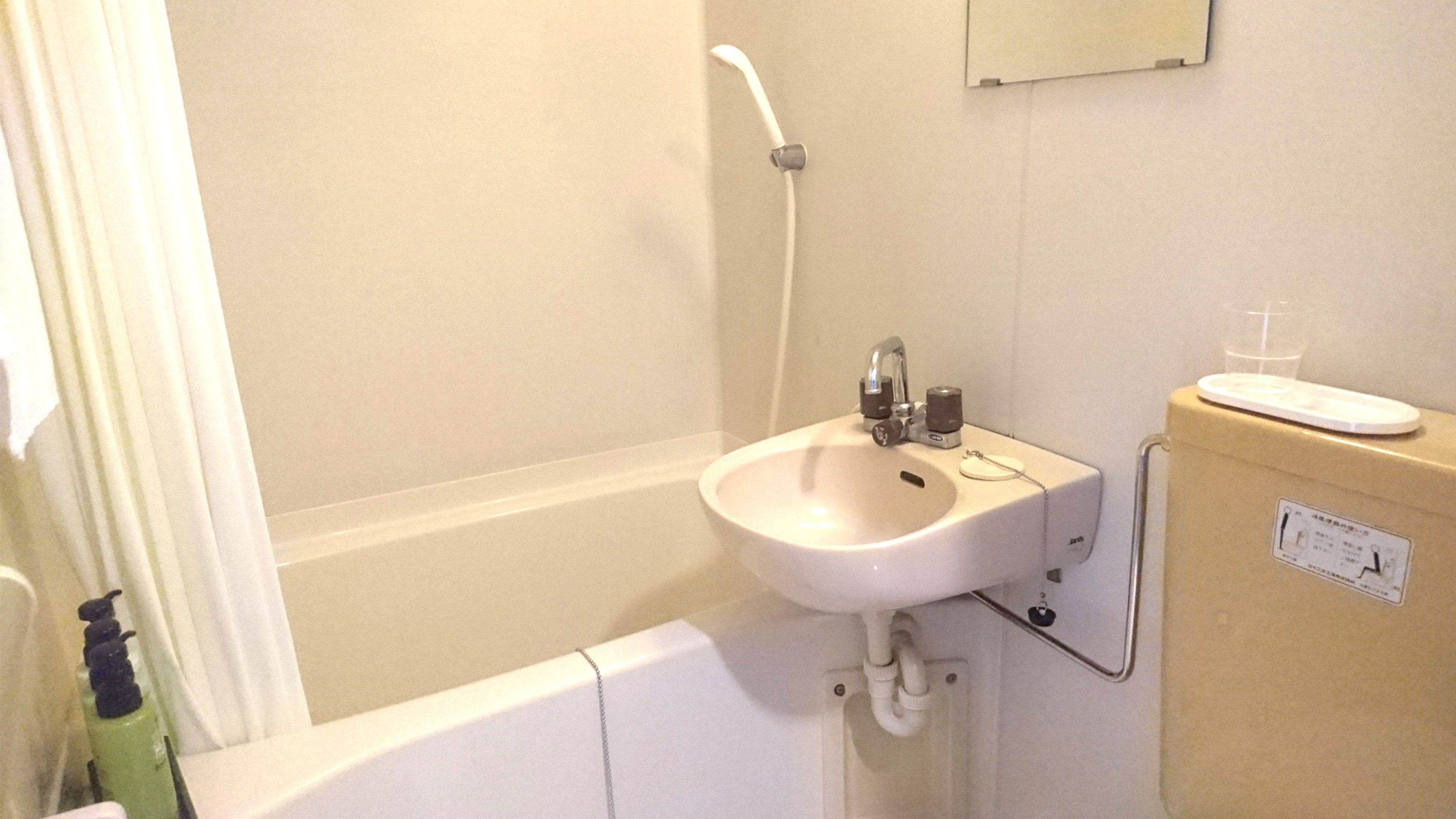 Un baño con lavamanos blanco, ducha e inodoro.