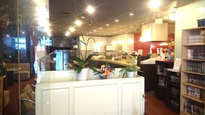 A restaurant with a counter, seating area, and a bookshelf. - Royal Inn Shinyamaguchi (Yamaguchi)