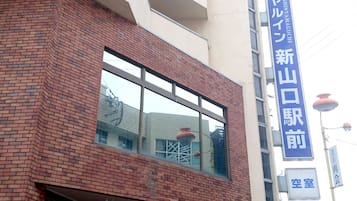 Un edificio con fachada de ladrillo y ventanas grandes. Hay un letrero con caracteres japoneses y un cartel azul encima.