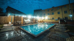 Piscina con sillas de descanso y una zona cubierta con iluminación.