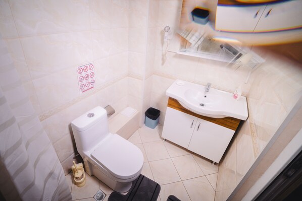 Un baño pequeño con inodoro, lavamanos y cubo de basura.
