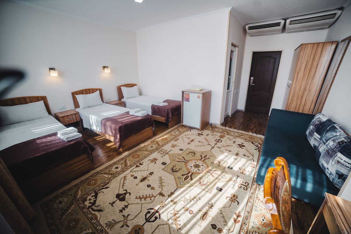 A hotel room with two beds, a small desk, a wardrobe, and a patterned carpet.