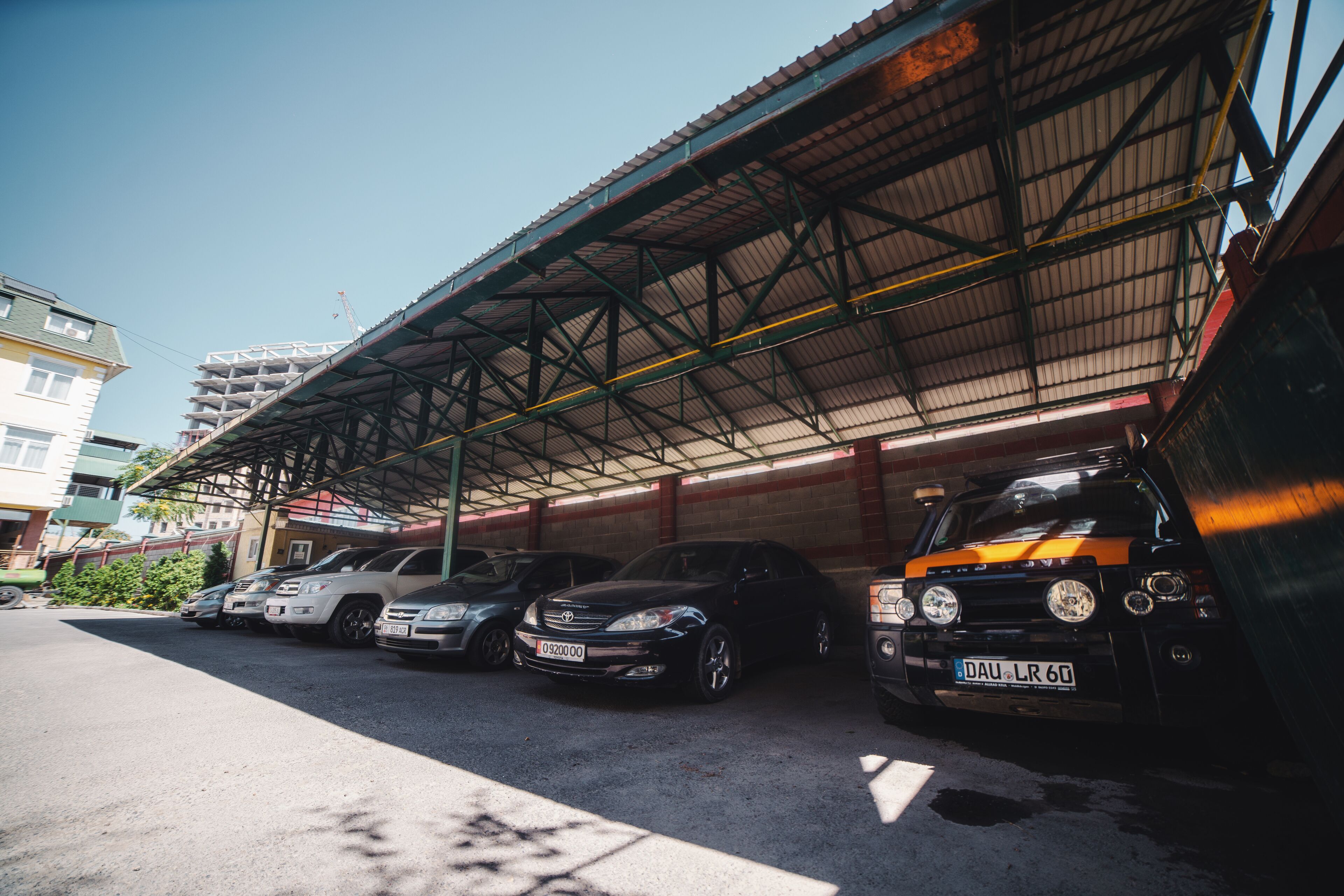 A covered parking area with multiple cars parked under a metal roof.