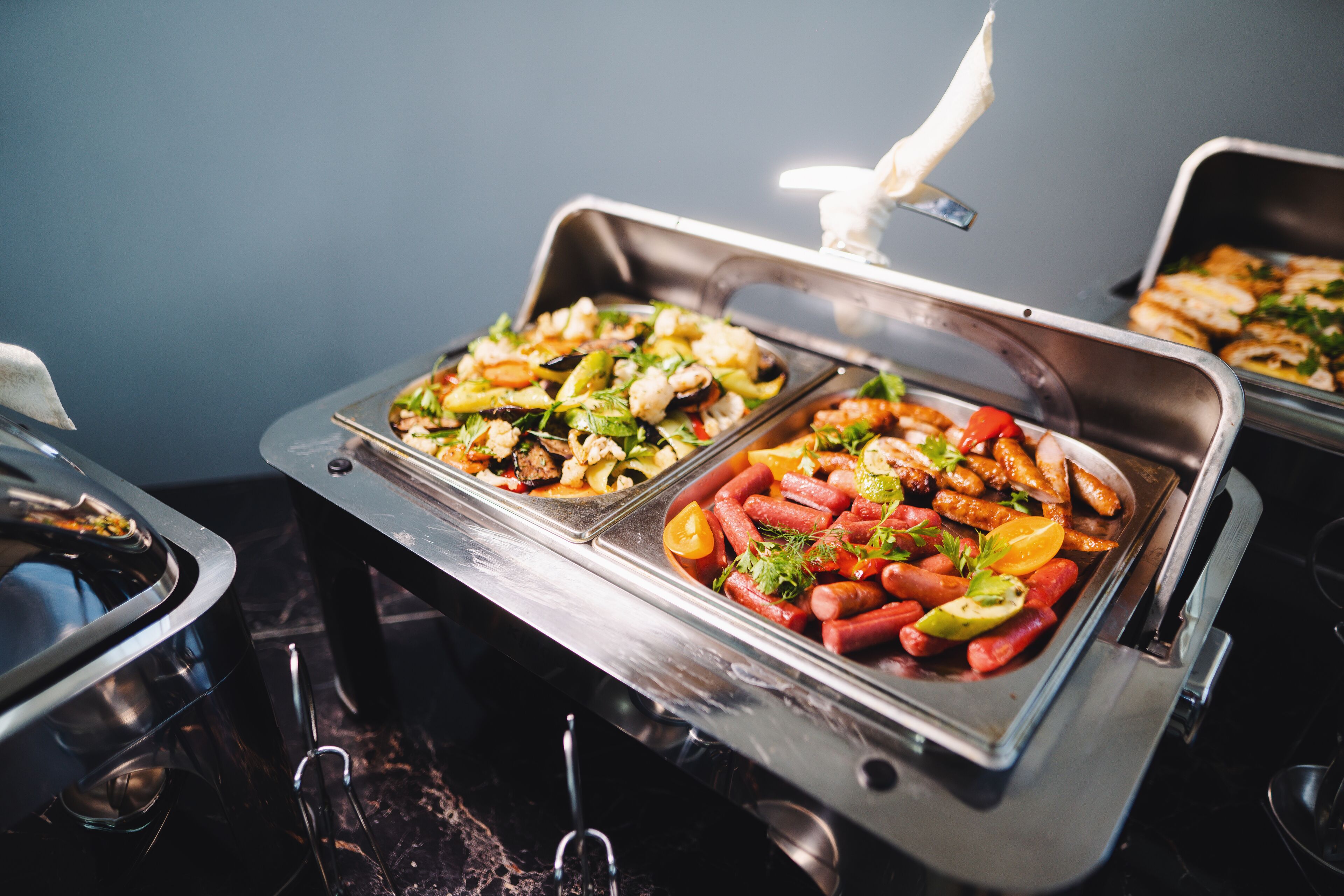 A buffet with various dishes including sausages, vegetables, and seafood.