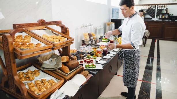 Un montaje de buffet con diversos alimentos y una persona sirviendo.
