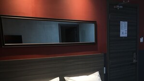 A hotel room with a bed, two pillows, a headboard, a mirror, and a door with a notice on it. - Express Inn - Osmeña (Cebu City)