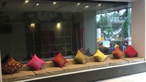 A modern interior with a glass partition, a sofa with colorful cushions, and a view of the street outside. - Express Inn - Osmeña (Cebu City)