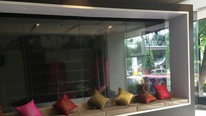 A modern interior with a seating area featuring a glass partition, a sofa with cushions, and a view of the outside. - Express Inn - Osmeña (Cebu City)