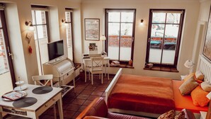 Una habitación de hotel compacta con kitchenette, zona de comedor, sofá y cama.