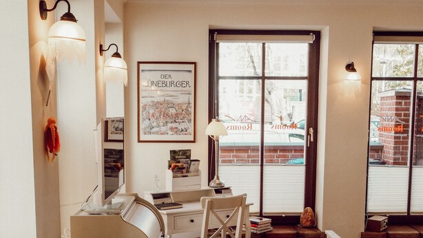 Una habitación acogedora con una mesa de comedor, sillas, un escritorio blanco y un ventanal con vistas a la calle.