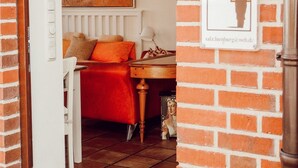 Habitación de hotel con pared de ladrillo, un cuadro de un paisaje urbano, una cama con una colcha roja y un letrero que dice "Backstein Paradies".