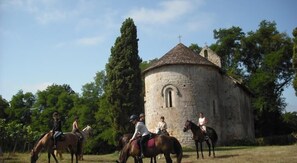A stone building with a circular tower and a cross on top, surrounded by trees. - Relais du Haget (Cravenceres)