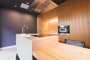 Eine moderne Küche mit Kochinsel, eingebautem Ofen und Wand-Fernseher.