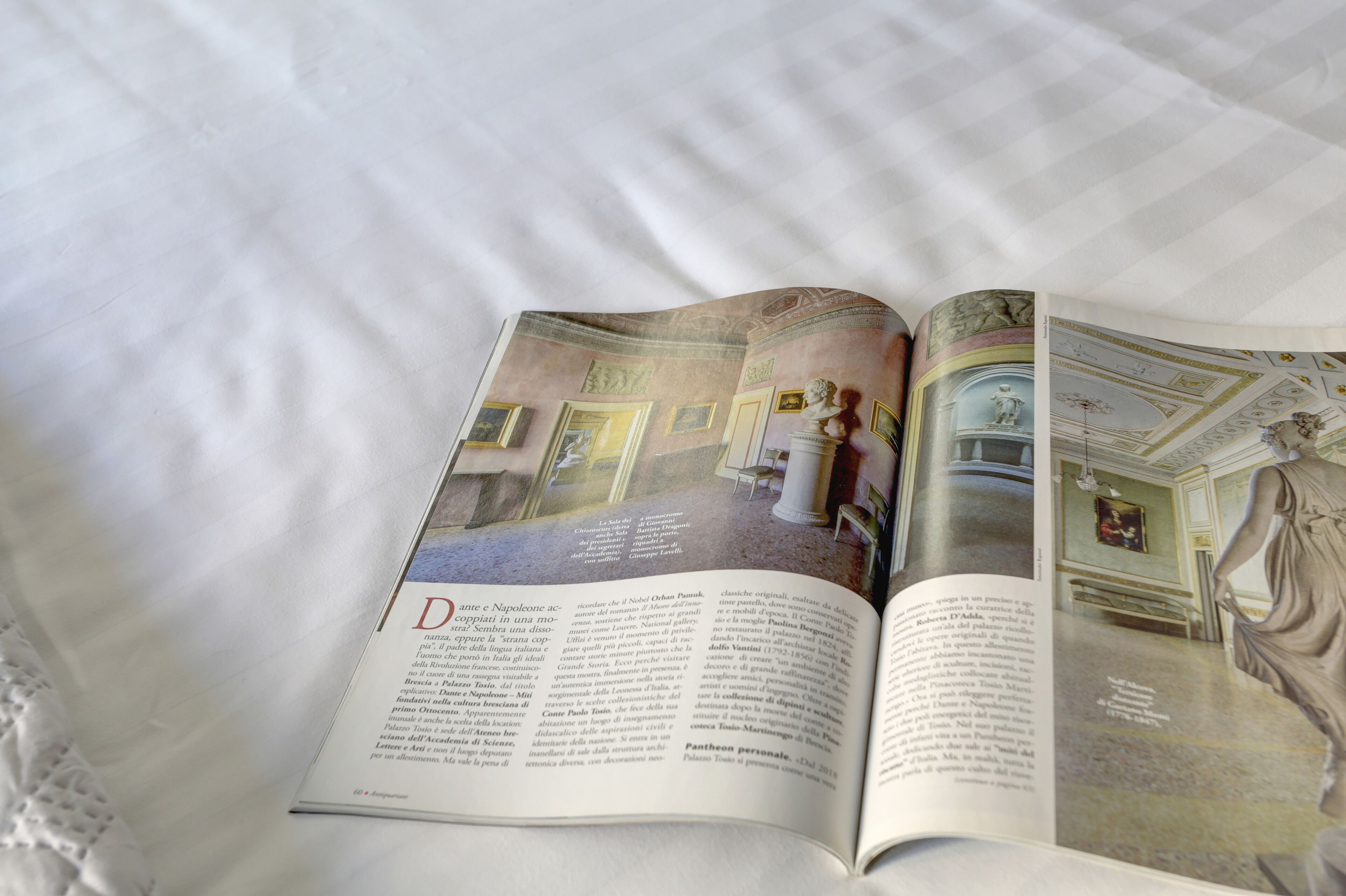 An open book with a page displaying a room with a statue, a bust, and a painting.