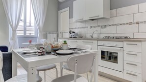 A modern kitchen with white cabinets, a built-in oven, and a window with white curtains.
