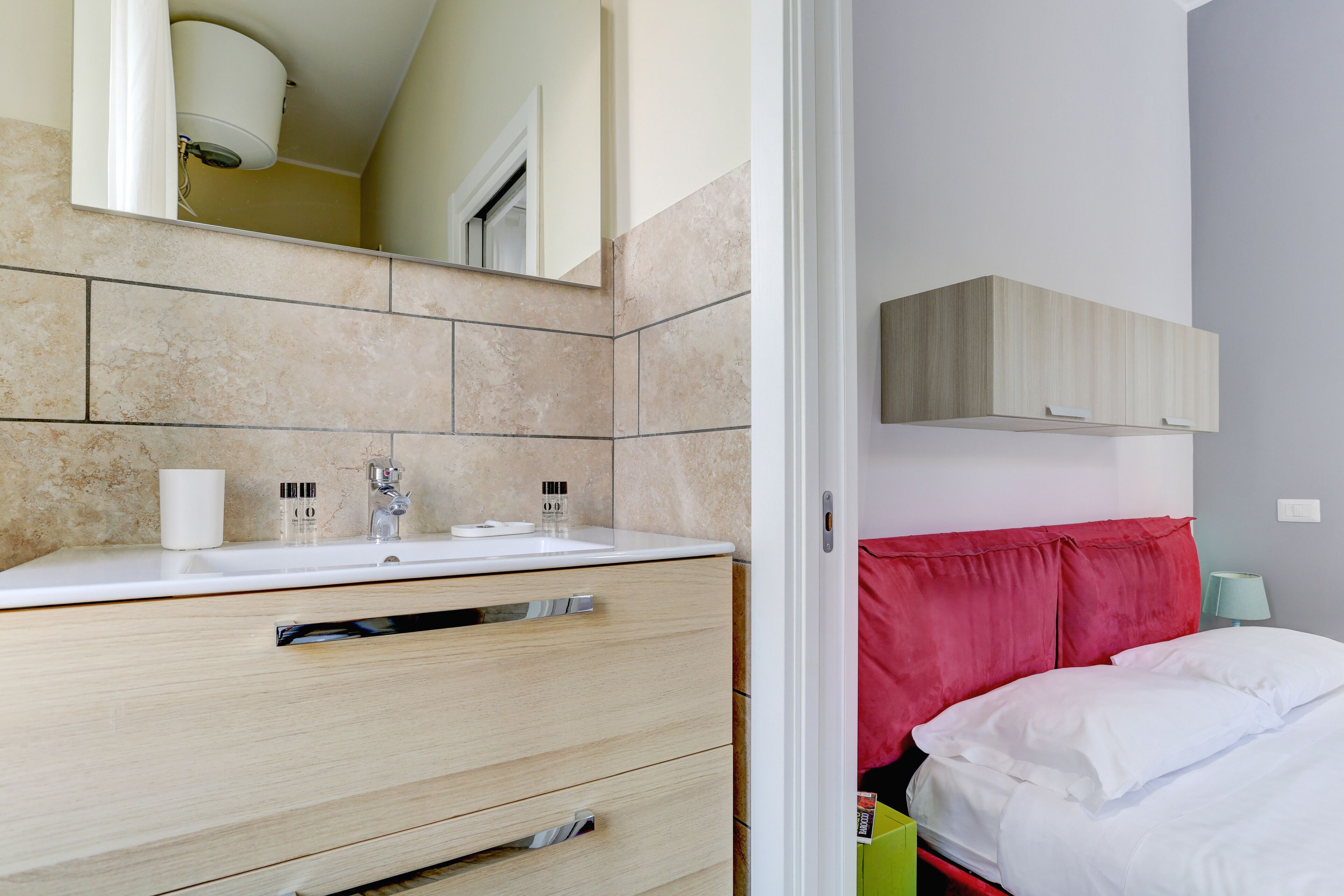 A modern bathroom with a white sink, beige tiles, and a large mirror.