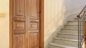 A wooden double door with a brass handle and a light switch on the wall to the left.