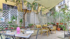 An outdoor patio with a table and chairs, surrounded by potted plants and a lattice fence.