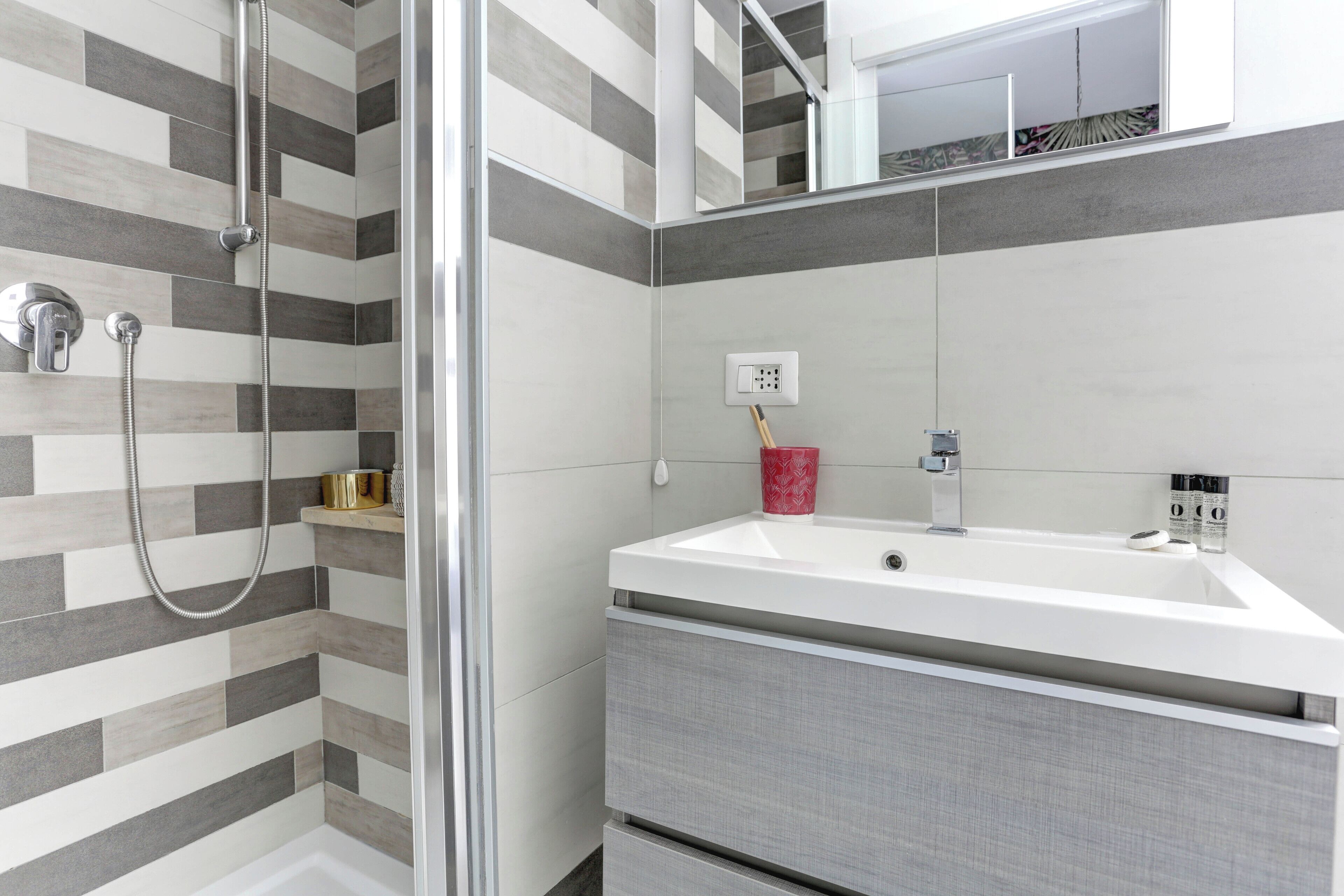 A modern bathroom with a shower, a sink, and a mirror.
