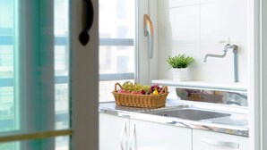 Una cocina con ventana, un lavabo y una cesta de fruta sobre la encimera.