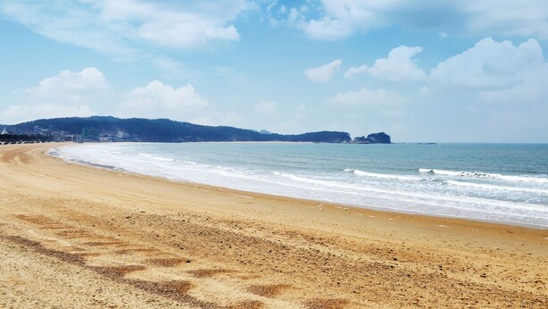 Una playa con arena y olas suaves.
