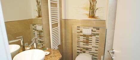 Un baño con lavamanos, inodoro y toallero.