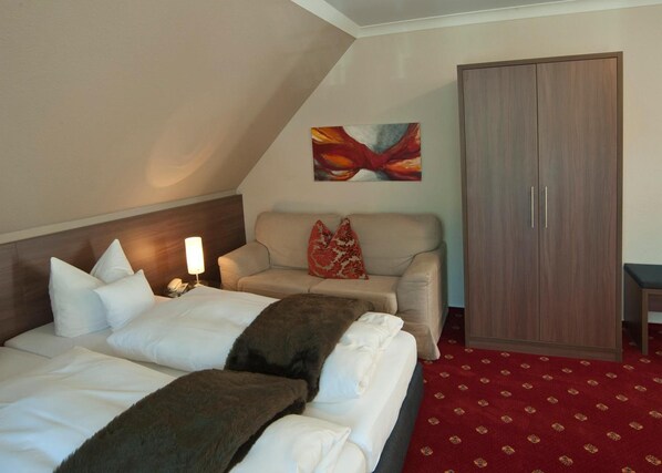 Una habitación de hotel con cama, sofá, armario y un cuadro en la pared.