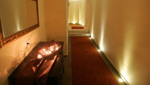 A hotel hallway with a mirror, a bench, and a red carpet leading to a door. - Isselhorster Landhaus (Guetersloh)