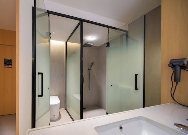 A modern bathroom with a glass-enclosed shower, a toilet, and a hairdryer mounted on the wall. - Yishan Inn (Zhangjiajie)