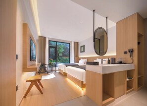 Ein modernes Hotelzimmer mit Bett, Nachttisch, Spiegel und einem großen Fenster.