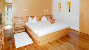 Une chambre à coucher avec un lit en bois, des tables de chevet, une commode, un tapis blanc et une armoire en bois.