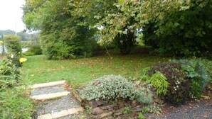 A garden with a stone pathway leading to a wooden bench. - La Guguenaie (Beganne)